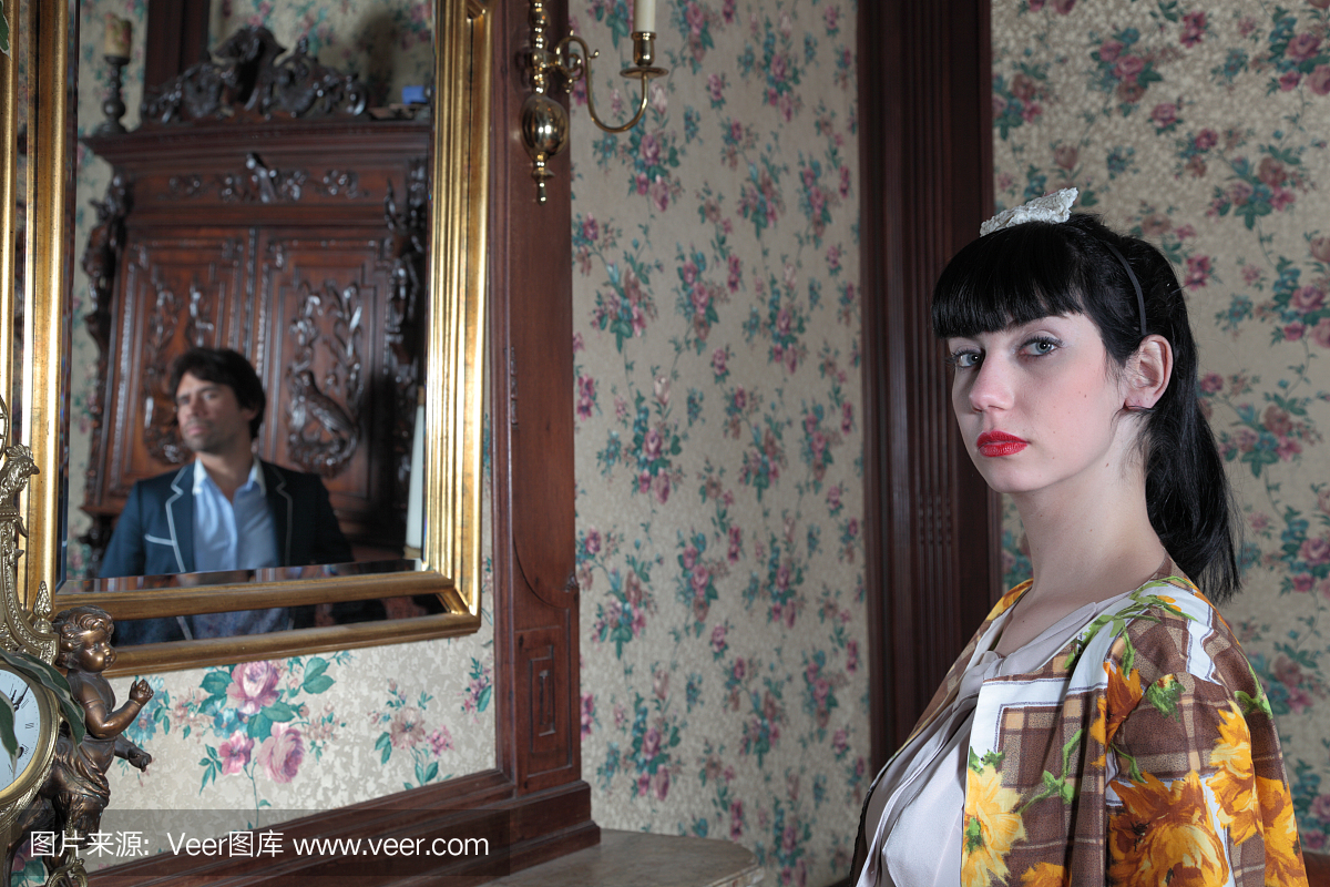 黑发西班牙女士复古的房间与男性反映在镜子