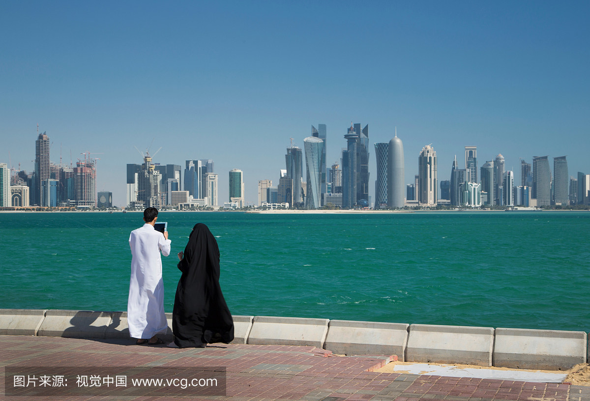 男人和女人看着摩天大楼在水,多哈,卡塔尔