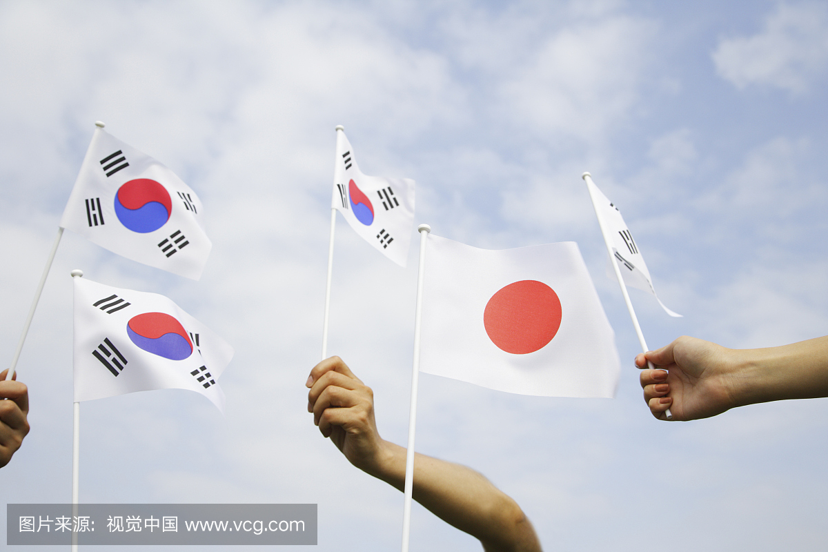 三个人拿着韩国国旗和日本国旗反对天空,低角