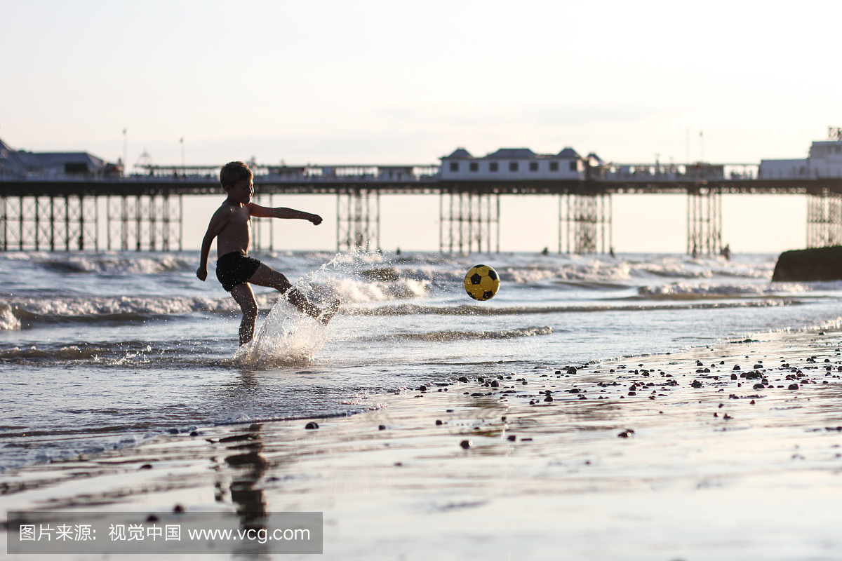 男孩在沙滩上踢足球