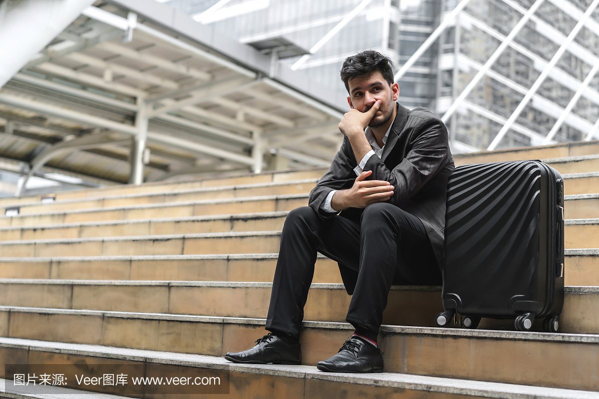 坐在楼梯与行李的商人在与决心和信心一起使用