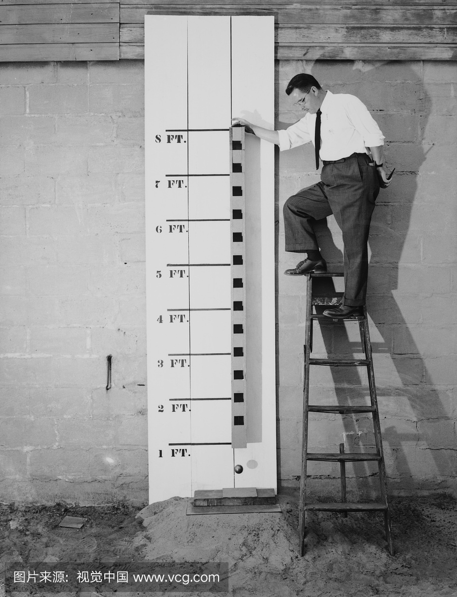 男子站在梯子上进行测量