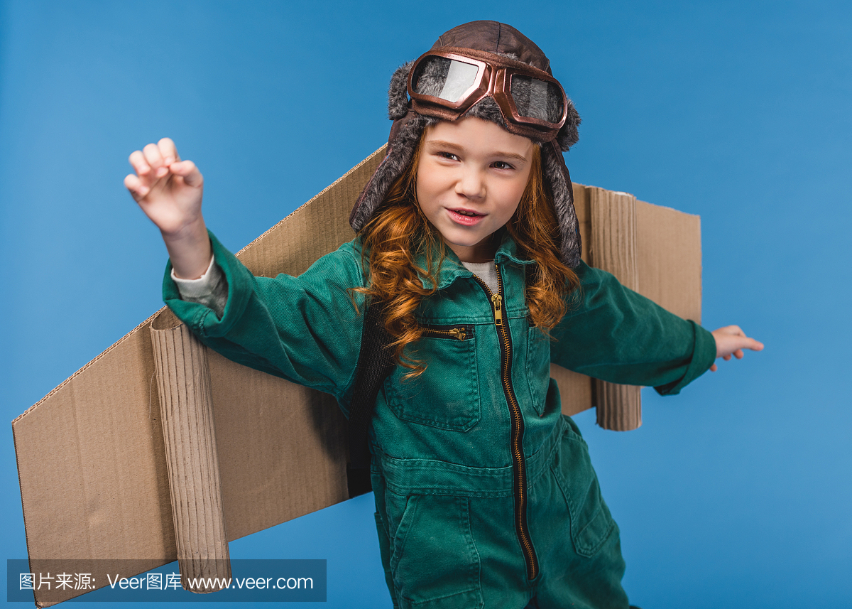 可爱的孩子在飞行员服装与手工纸飞机翅膀上蓝