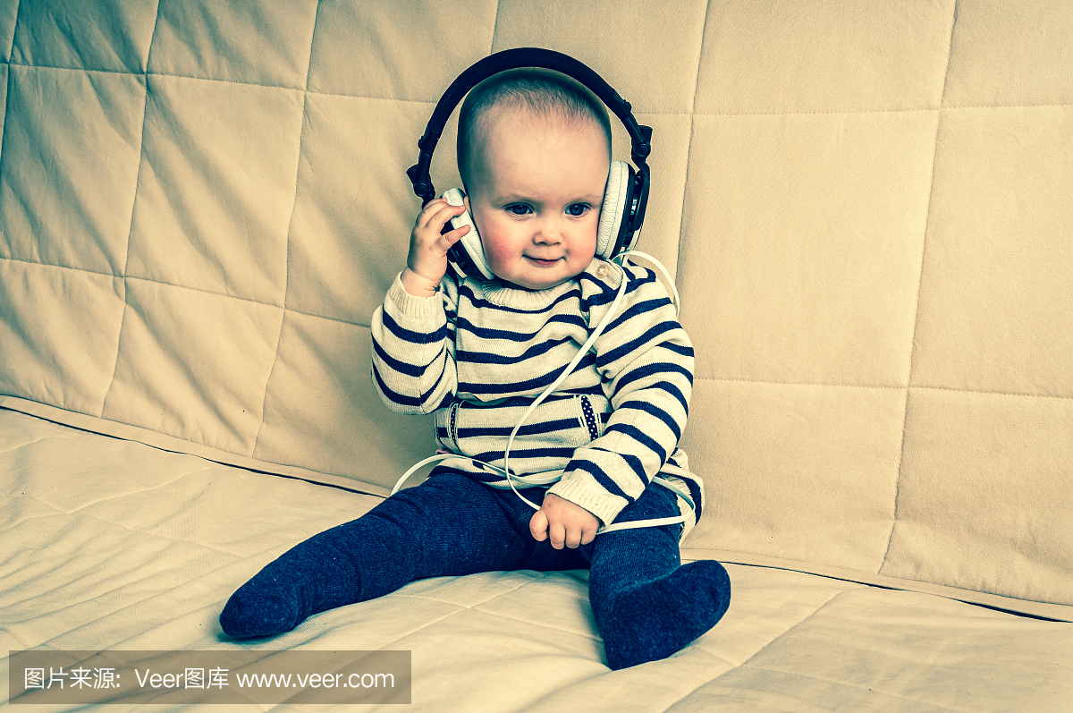 带耳机的可爱宝宝在家听音乐