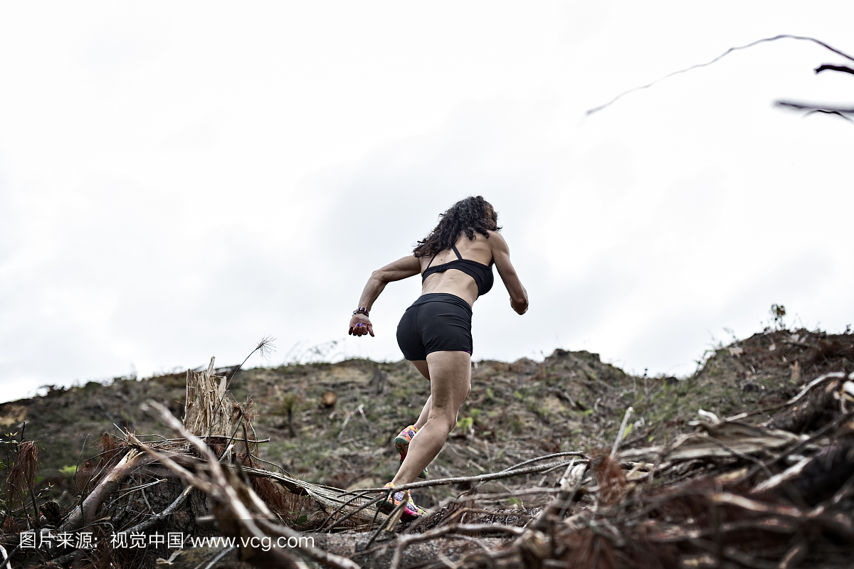 毛利人的女人跑过日志和树枝的小山。
