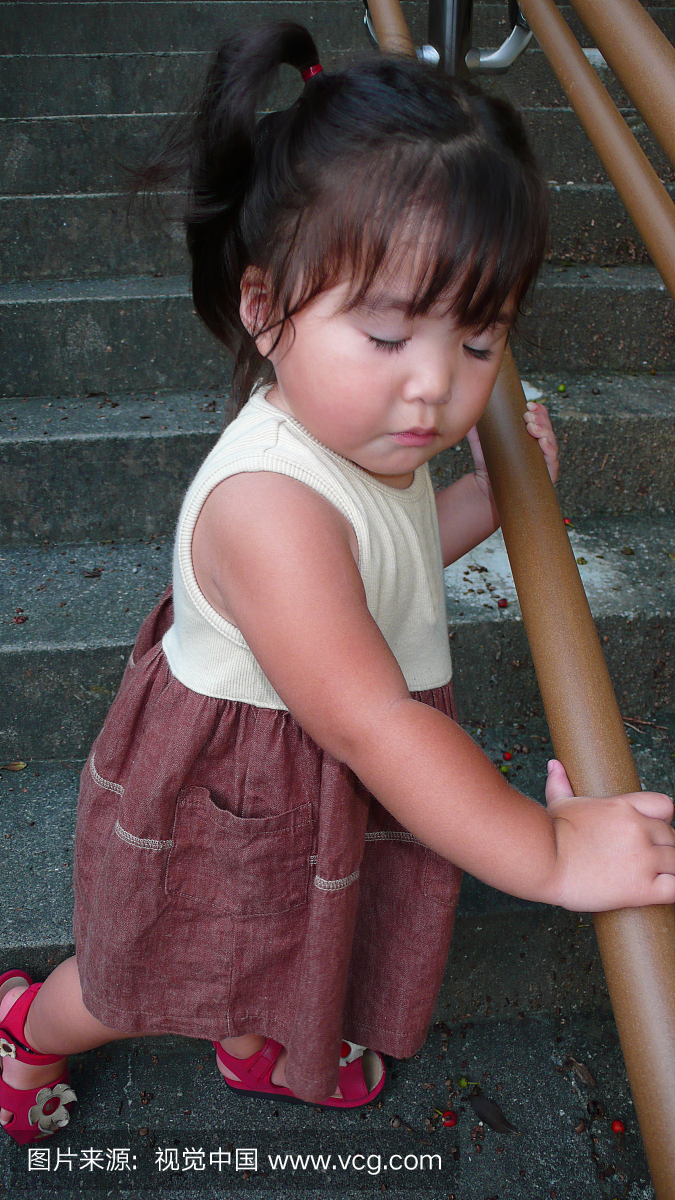 An one-year-old girl standing on the steps
