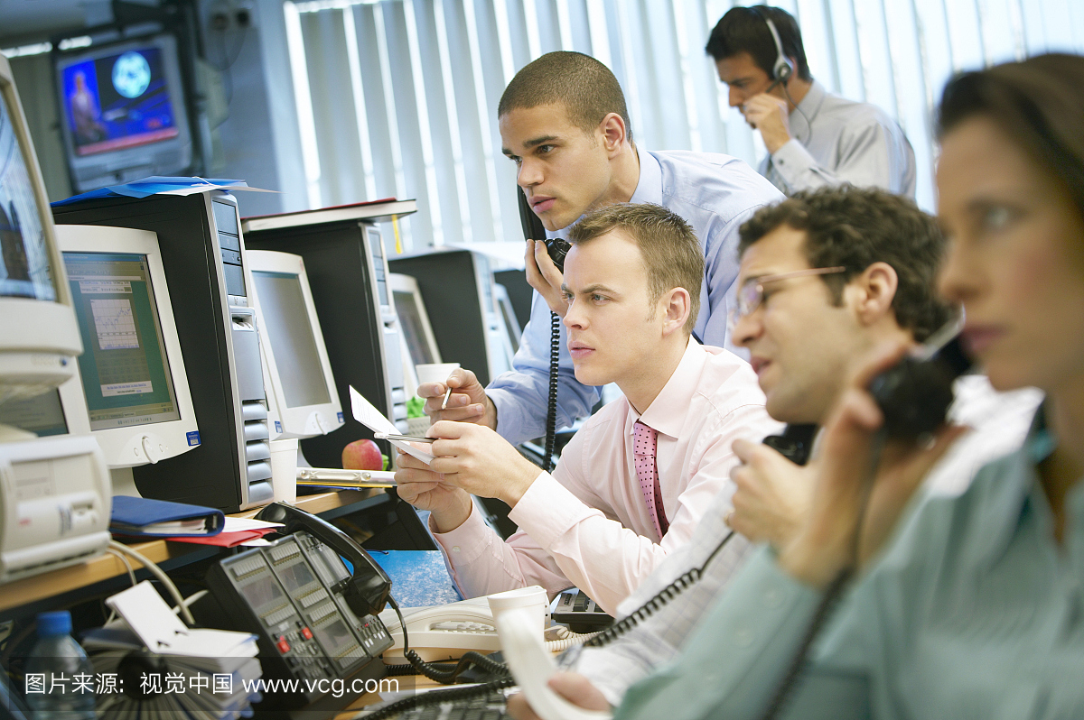 股票交易员团队坐在办公桌上工作电话