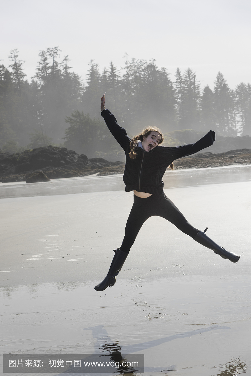 一个女孩在一个潮湿的海滩上空中跳跃