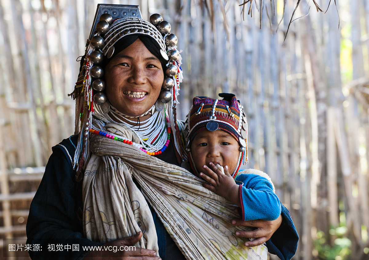 一名妇女和她的婴儿从Akha部落村穿着传统的