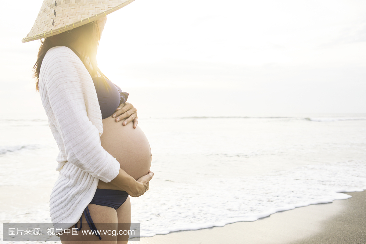 亚洲孕妇比基尼和草帽在海滩上