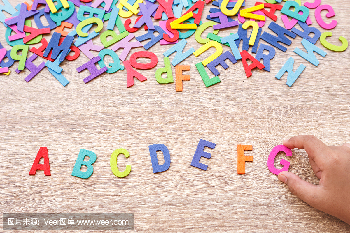 丰富多彩的木制字母表和手排序在G上灰色的木
