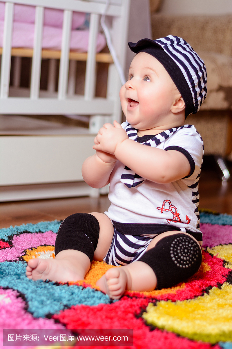 一个漂亮的婴儿穿着条纹衬衫和帽子坐在房间的
