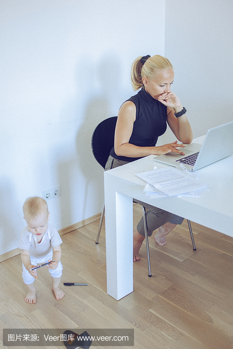 当她的宝宝在她身边玩耍时,在家工作的女人