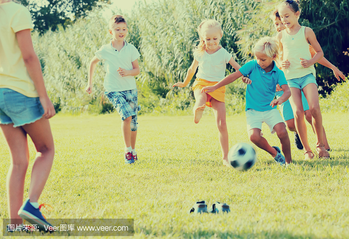 Group of active kids playing football together on
