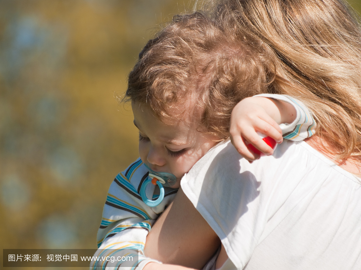金发碧眼的婴儿用奶嘴抱着他的母亲