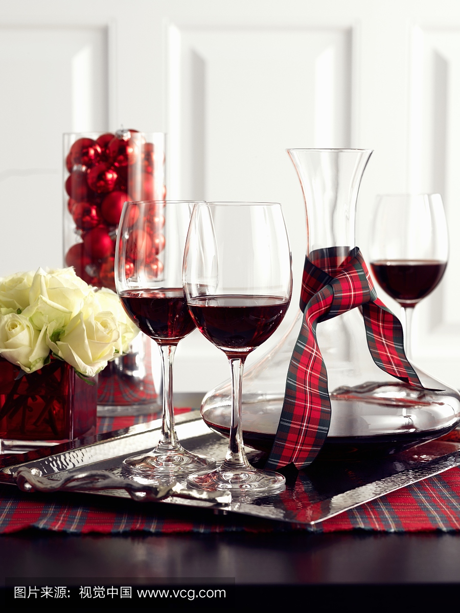在圣诞节装饰的桌子上的玻璃和玻璃瓶中的红葡