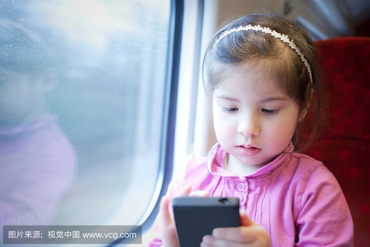 火车上的小女孩,在智能手机上玩游戏