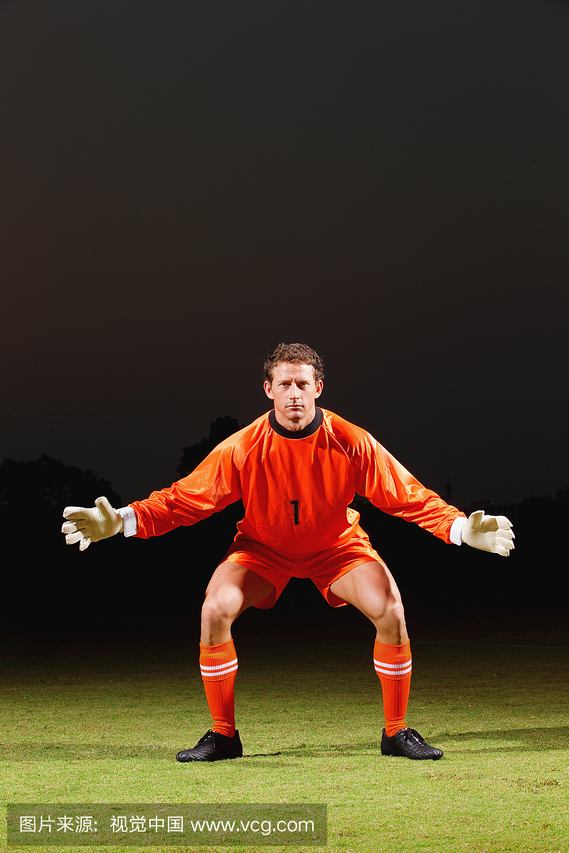 橙色制服站在足球场的守门员