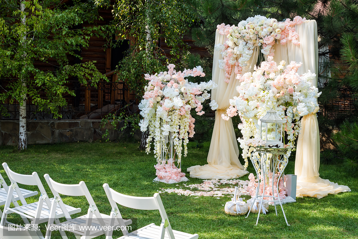 用布和花装饰的婚礼拱门户外。美丽的婚礼成立