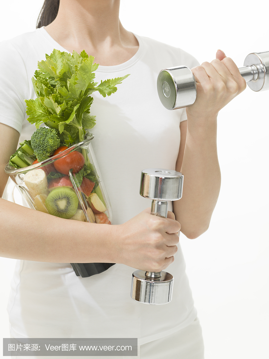 拿着哑铃和蔬菜榨汁机的女人