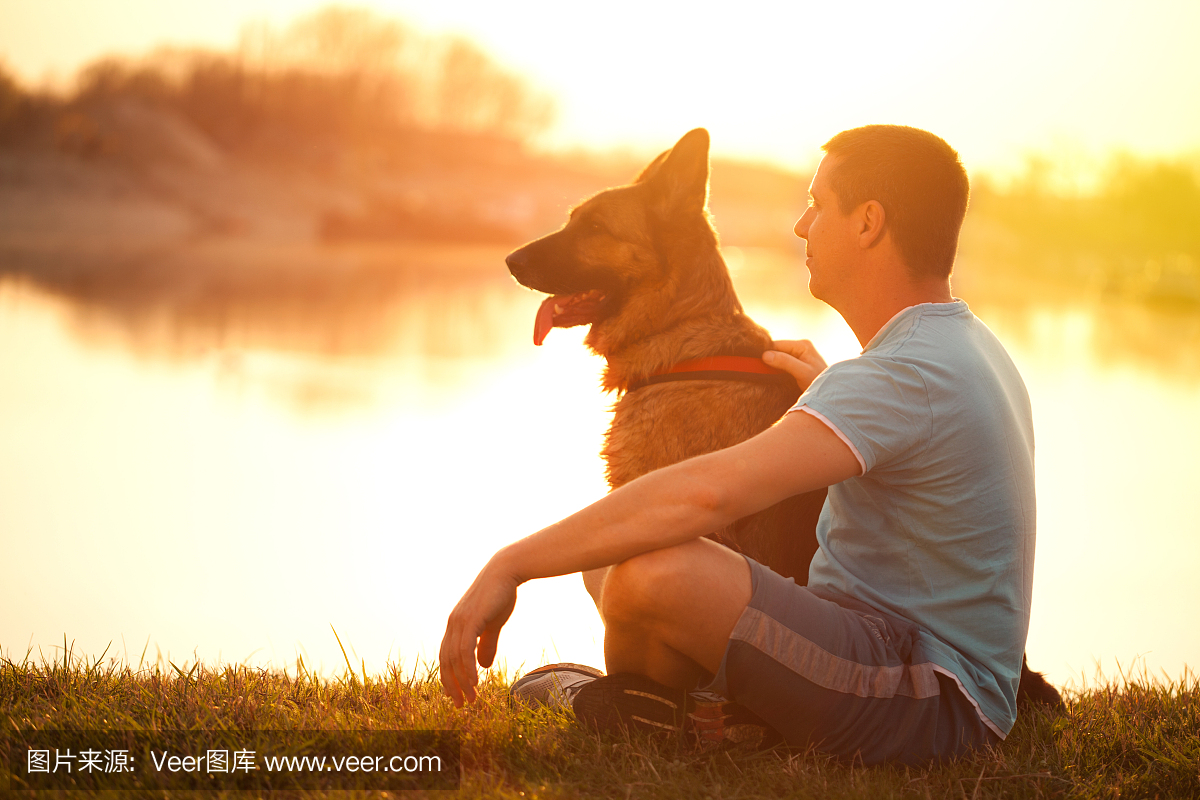 轻松的男人和狗享受夏天的日落或日出