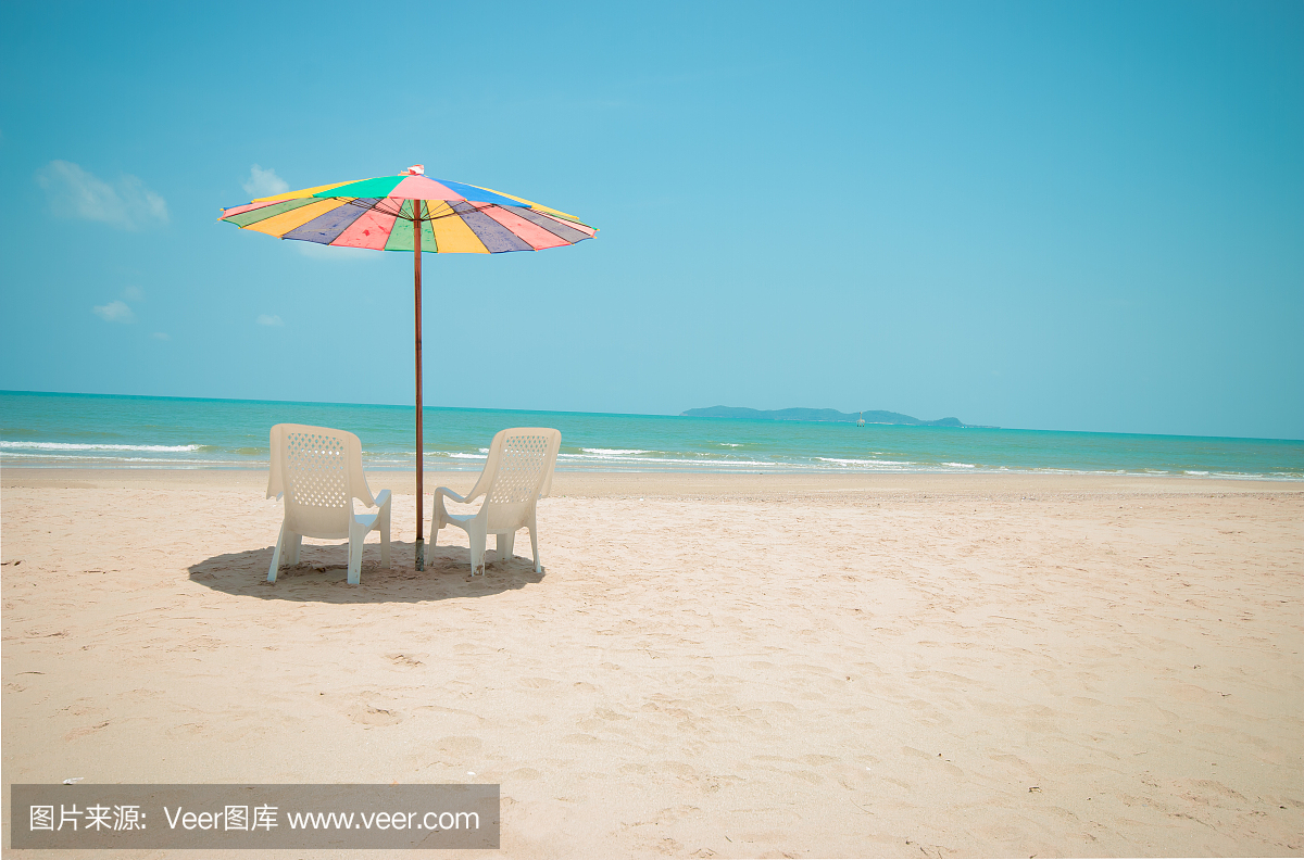 两个白色休闲椅与五颜六色的太阳伞海滩