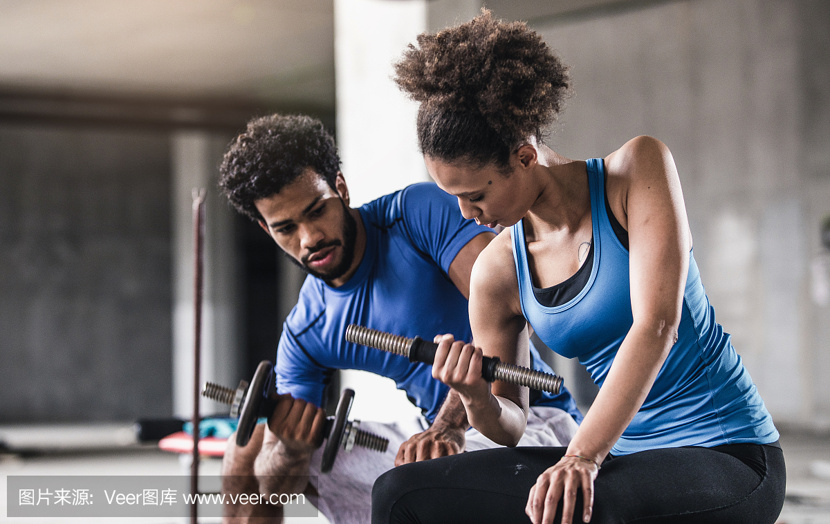 年轻女子举重与个人教练在她旁边