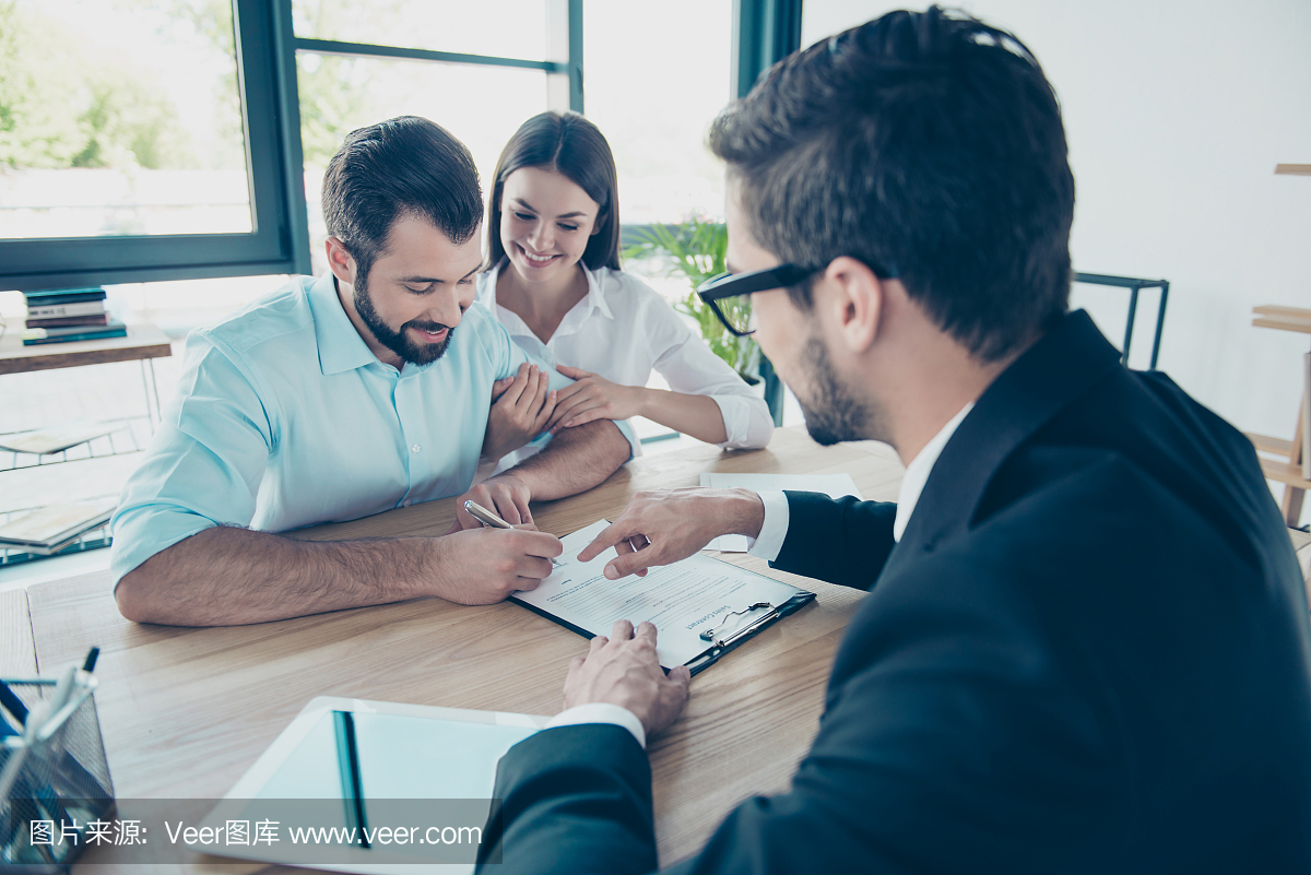 商务会议。幸福的夫妇正在购买新房子,年轻人有胡子的吸引力深色律师穿正式礼服提交合同签字,他们在他的办公室