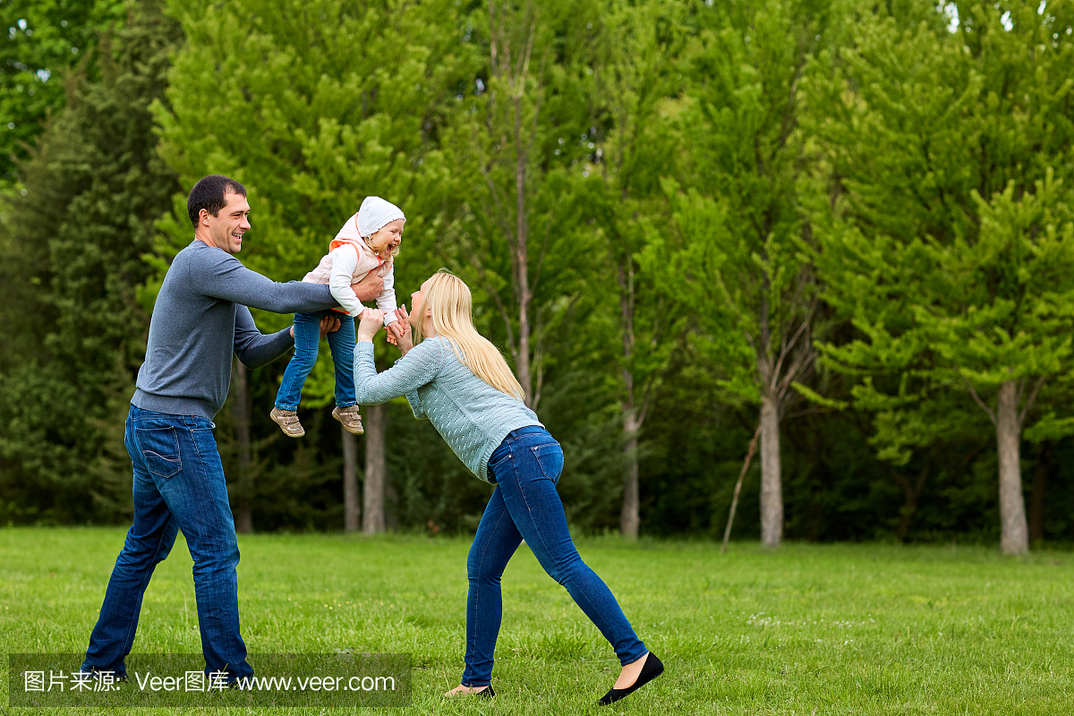 父母与孩子一起玩兴奋的在公园里。幸福的家庭