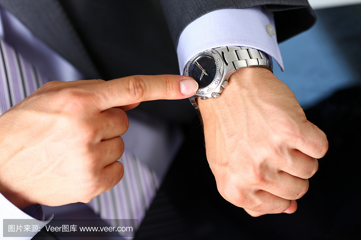 穿着西装和领带的男子在银色手表上查看时间