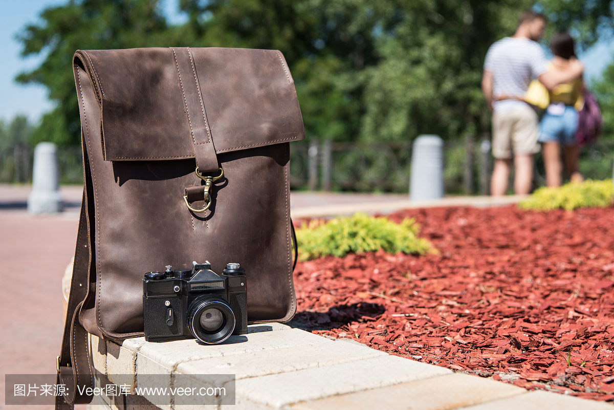时尚棕色皮包和户外相机的特写视图