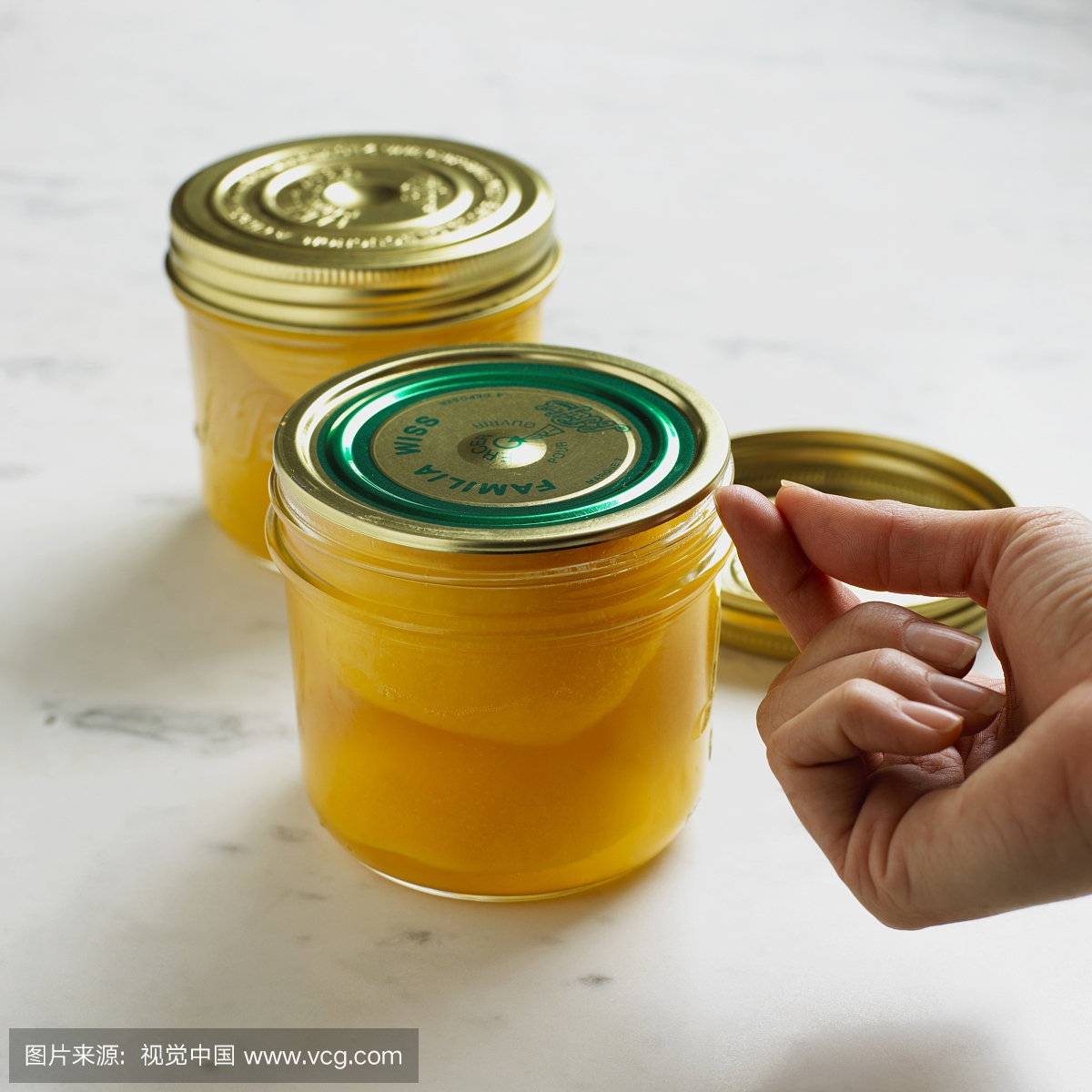 使用指甲测试盖子真空在一罐保存的桃子,特写