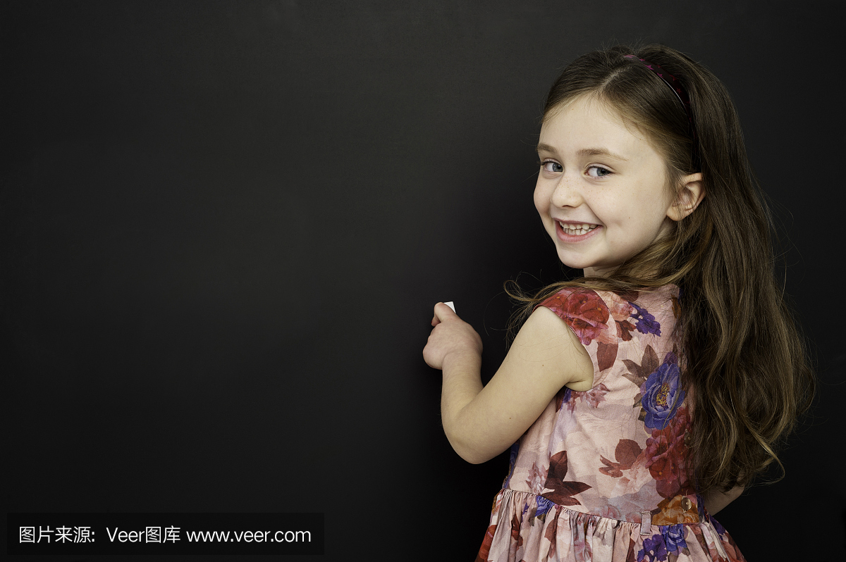 聪明的年轻女孩站在黑板上写字