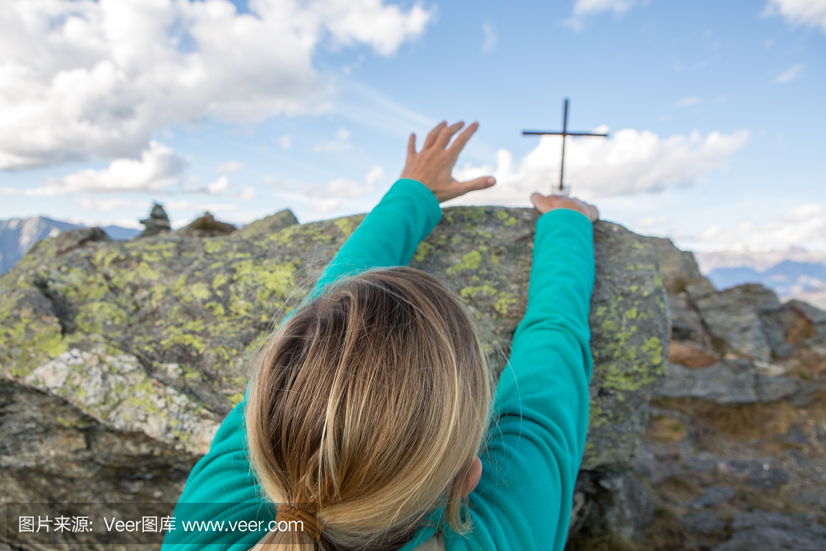 徒步旅行者女性抓住山峰顶部的最后一块岩石