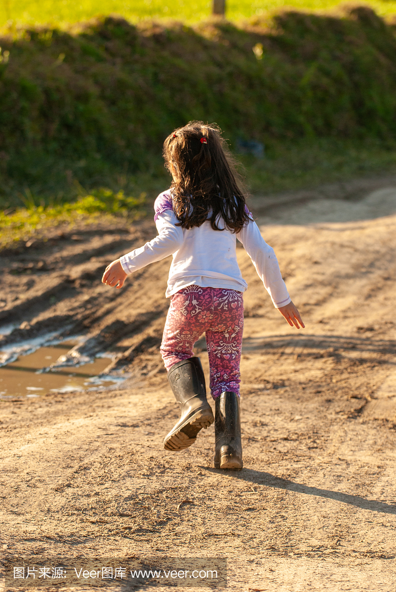 一个雨靴在泥上玩的小女孩