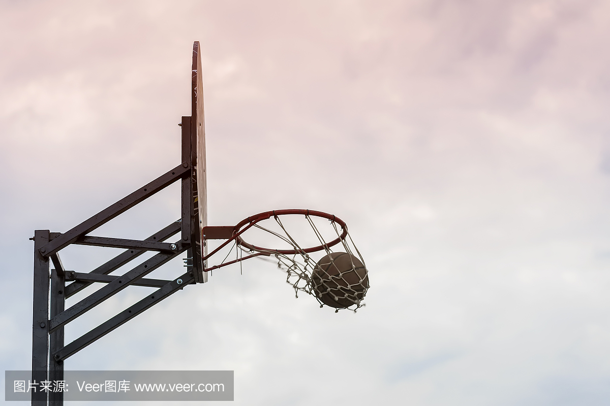 街头篮球比赛。篮球盾牌,球穿过天空背景上的