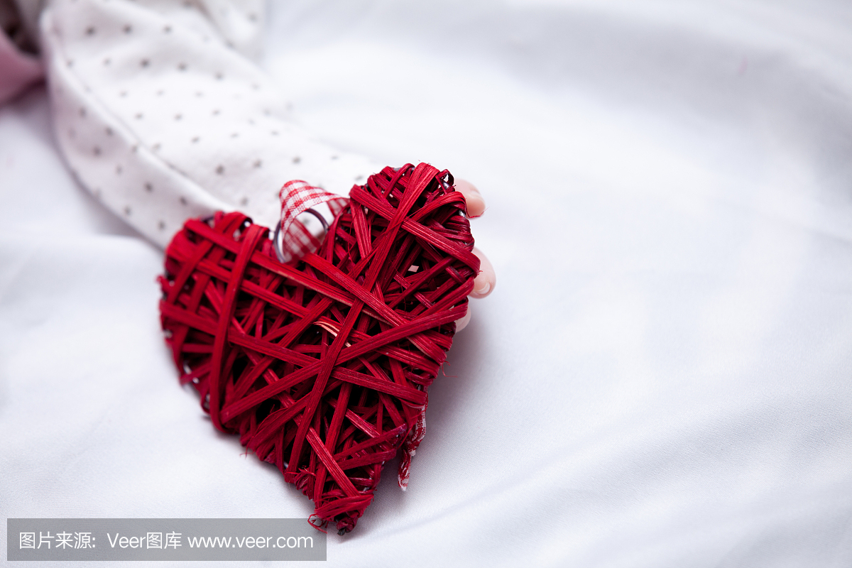 红色心形玩具的照片在白色毯子上的小宝宝的手