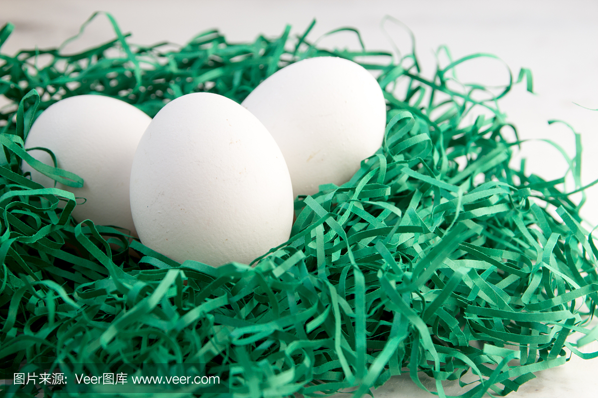 在绿皮书巢里的鸡蛋。三个白蛋