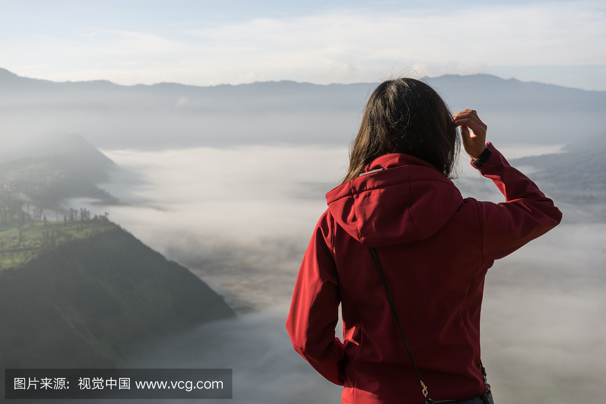 在雾天气中站在山上的女人的后视图