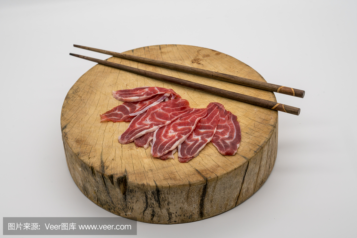 在木砧板上用新鲜切片牛肉后腿用筷子孤立在白