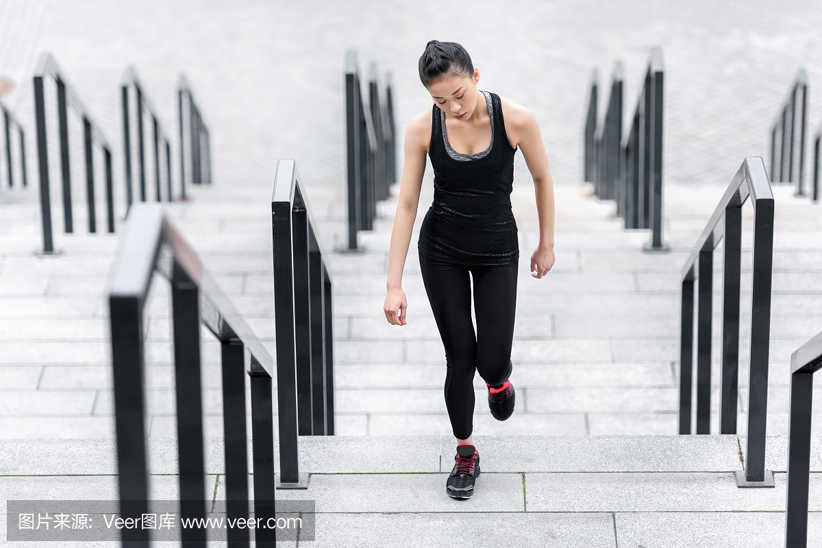 在体育场楼梯跑步运动服的运动年轻女子