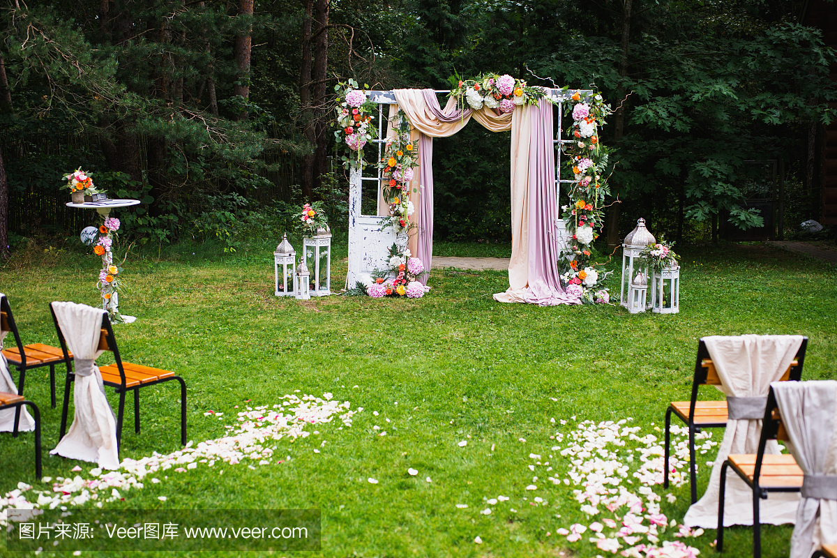 美丽的婚礼户外。装饰的椅子站在草地上。婚纱